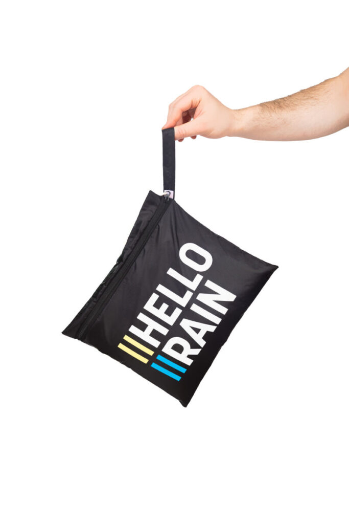 IMG_5287-Edit-Edit Persoon houdt opgevouwen budget regenbroek in handig opbergzak vast.