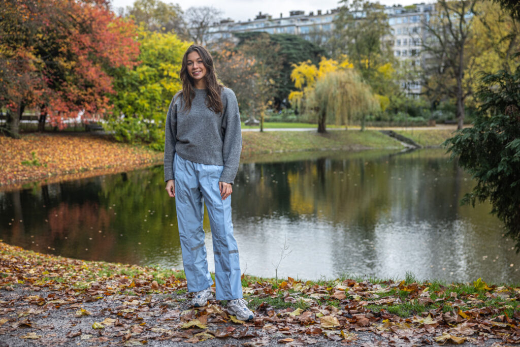 Vrouw staat in het park met een licht blauw premium regenbroek van Hello Rain.