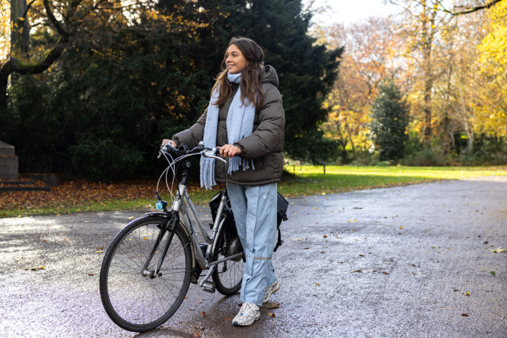 Persoon die voorbij wandelt met fiets in een regenbroek van Hello Rain.