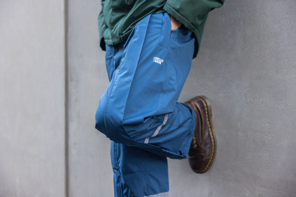 Close-up van man die tegen de muur staat in de Hello Rain regenbroek.