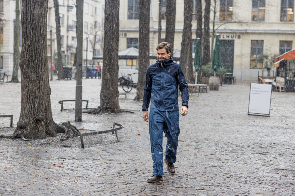 Man die in de sneeuw voorbij wandelt in een regenbroek van Hello Rain.