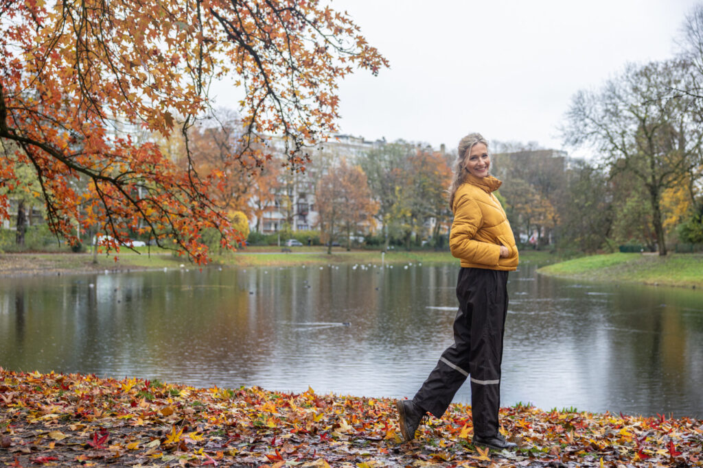 Zijprofiel van een vrouw die de waterdichte Hello Rain regenbroek draagt in het park.