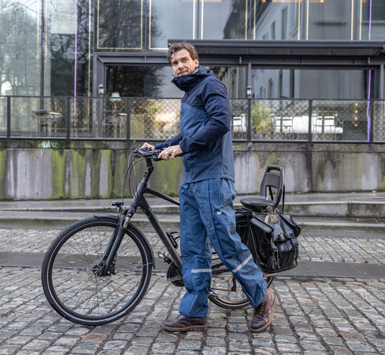 man wandelt met fiets voorbij in een Hello Rain premium regenbroek.