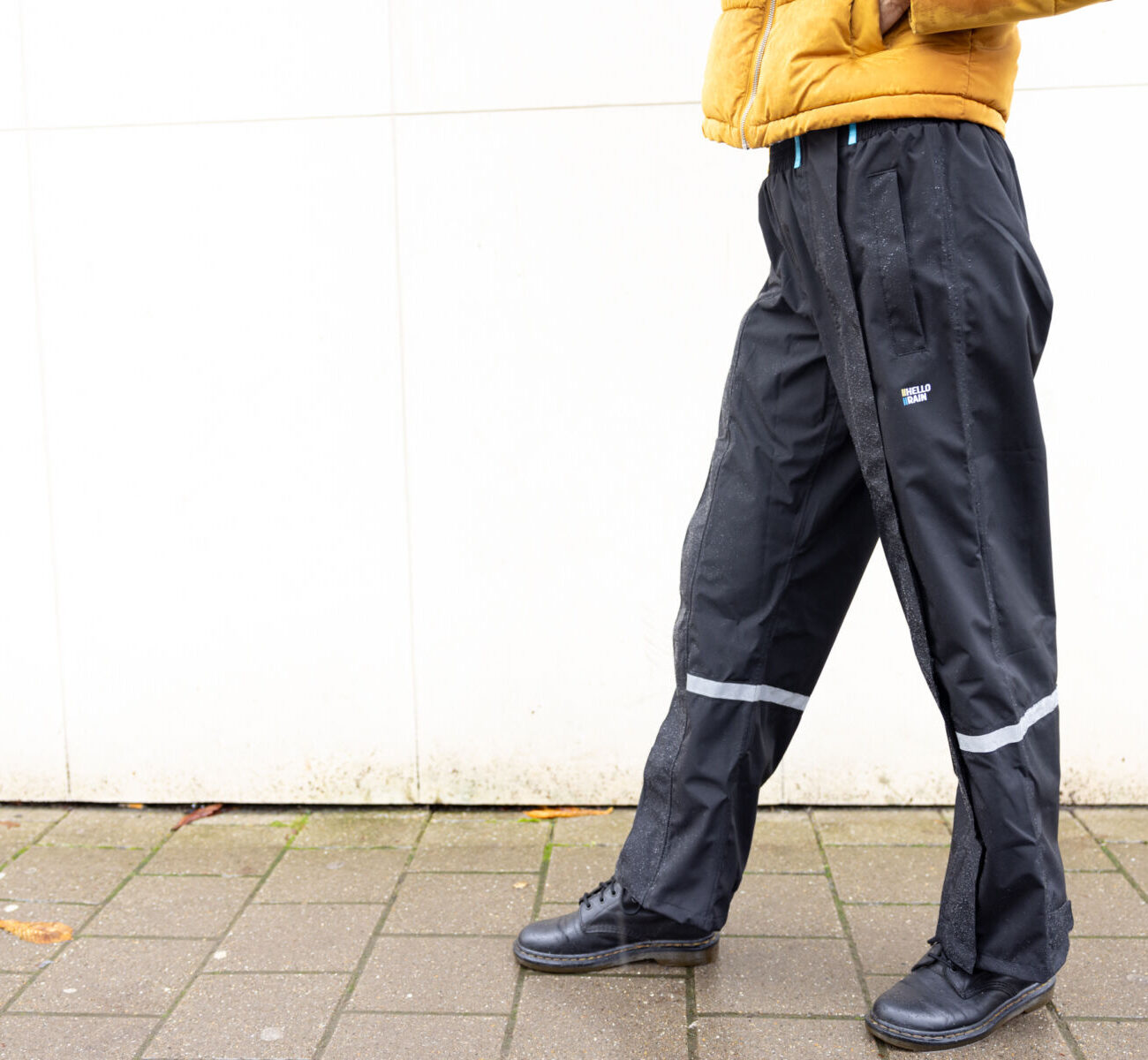 Vrouw staat in zijwaarts profiel met een premium regenbroek van Hello Rain.