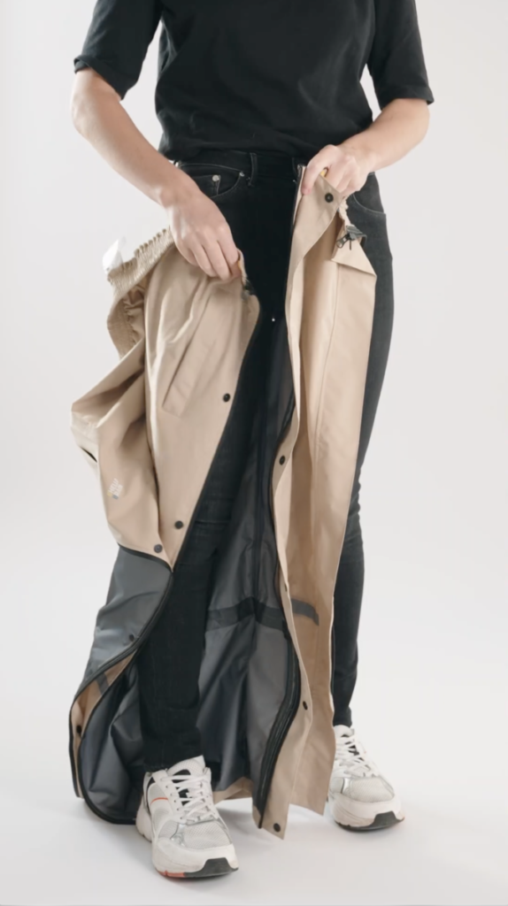 Persoon die de Hello Rain regenbroek aandoet met behulp van de innovatieve ritssluiting.