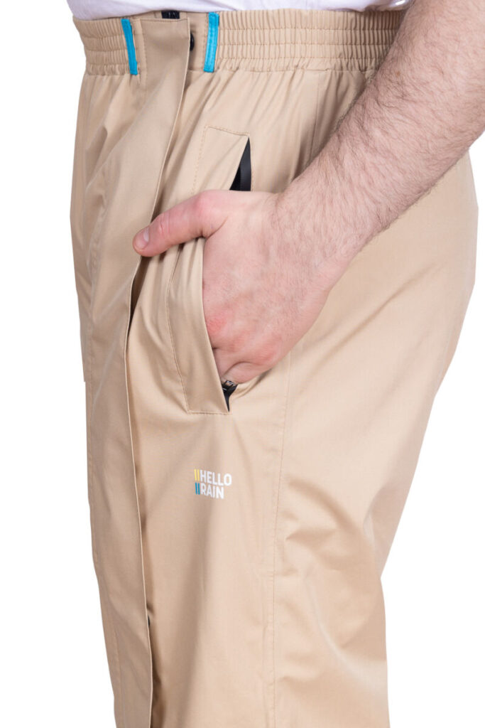 Close-up van man met handen in zakken in een beige premium regenbroek.