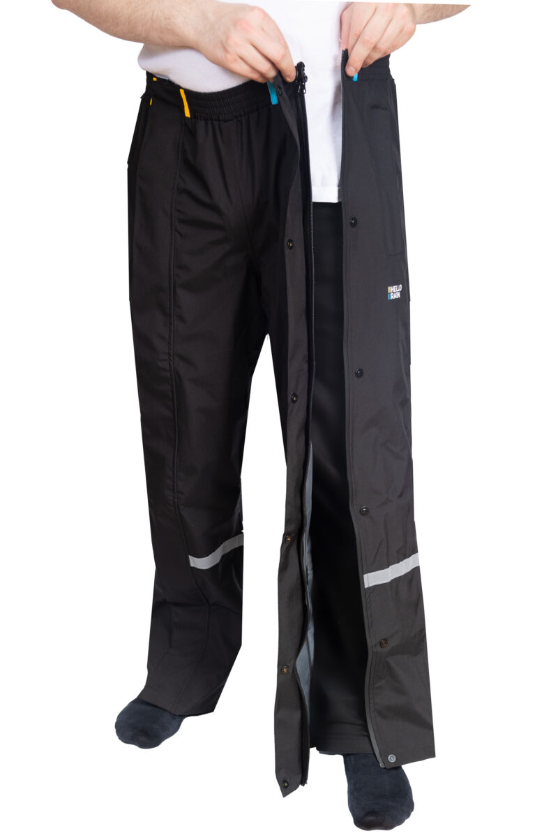 Product afbeelding van zwarte budget regenbroek waarbij de persoon de ritssluiting toe doet.