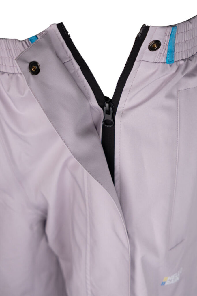 Close-up van ritssluiting aan de zijkant van een grijze premium regenbroek.